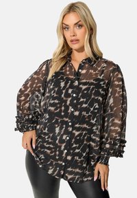Blusa nera trasparente con stampa astratta marrone e crema, chiusura a bottoni davanti e maniche gonfiate di tessuto con dettagli arricciati.