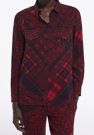 Skjorte med lange ærmer og knapper samt matchende bukser med rød og sort blandet dyreprint, ternet og paisley mønster, båret af en person.