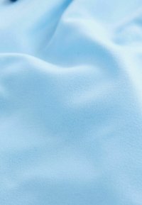 Tessuto blu chiaro che presenta una superficie liscia con una leggera elasticità. Il materiale sembra leggero ed è privo di fantasie o dettagli.