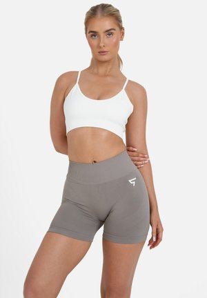 Lagani, rebrasti bijeli crop top uparen s kratkim hlačama viskog struka od glatke sive tkanine koje imaju logo detalj i teksturiranu površinu.