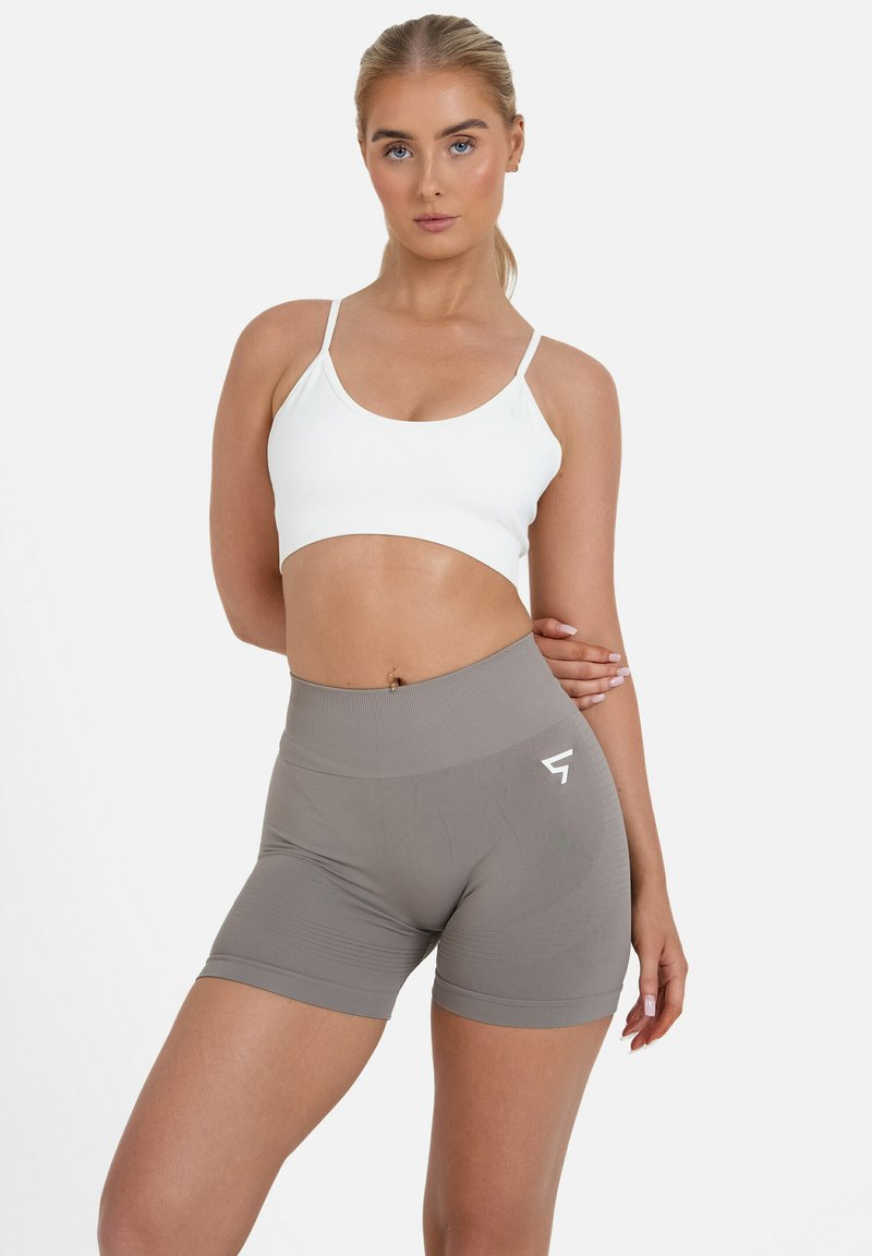 Lahka, rebrasta bela kratka majica, kombinirana z visokim gladkim sivim kratkimi hlačami, ki imajo logo in teksturirano tkanino.