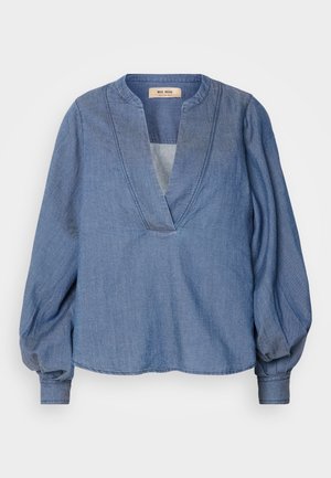 Lys blå denimbluse med dyp V-hals, ballongsleeves og avslappet passform. Har strukturert søm langs halslinjen og mansjettene.