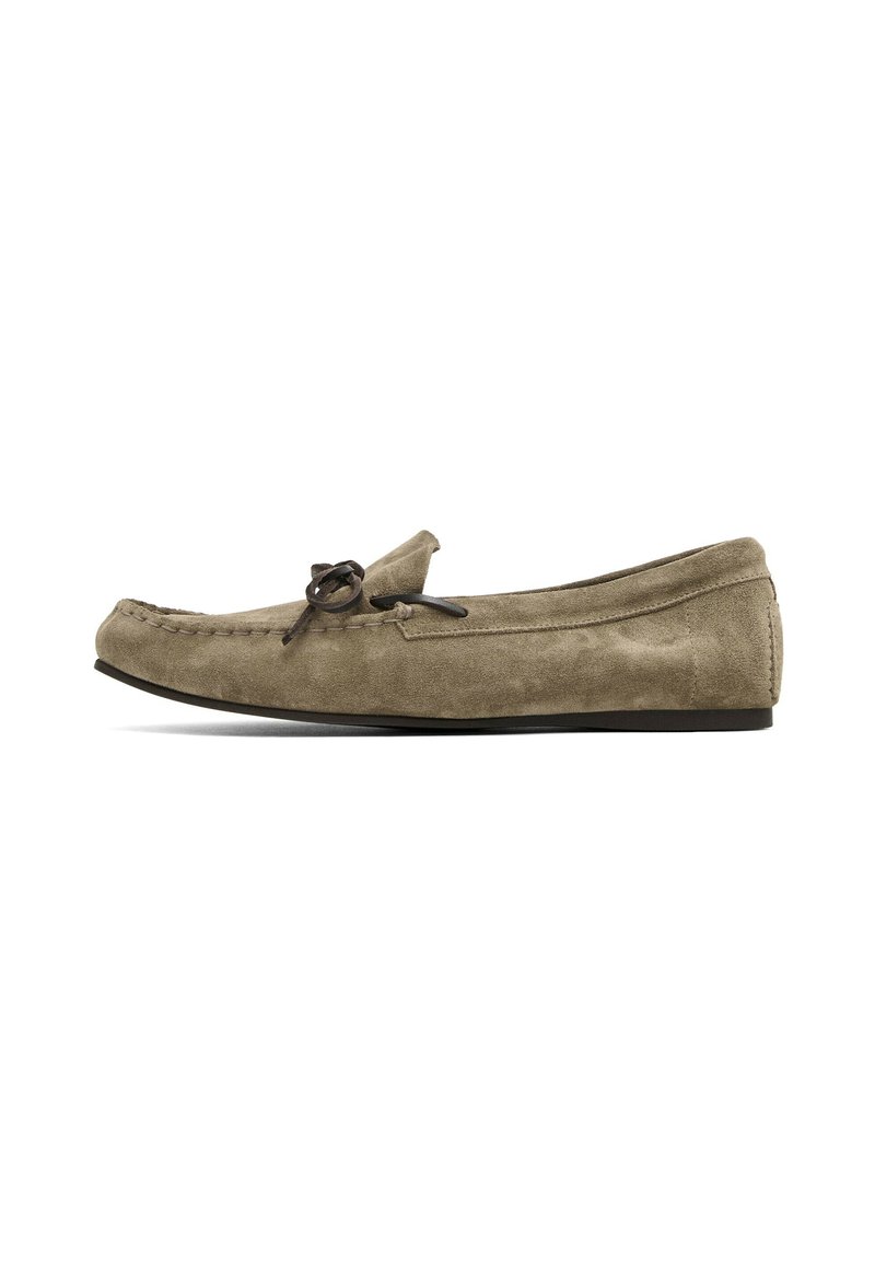 Hellbraune Wildleder Slipper mit abgerundeter Spitze, genähten Details und einer dekorativen Schnürsenkelfransen an der Vorderseite. Flache Gummisohle.