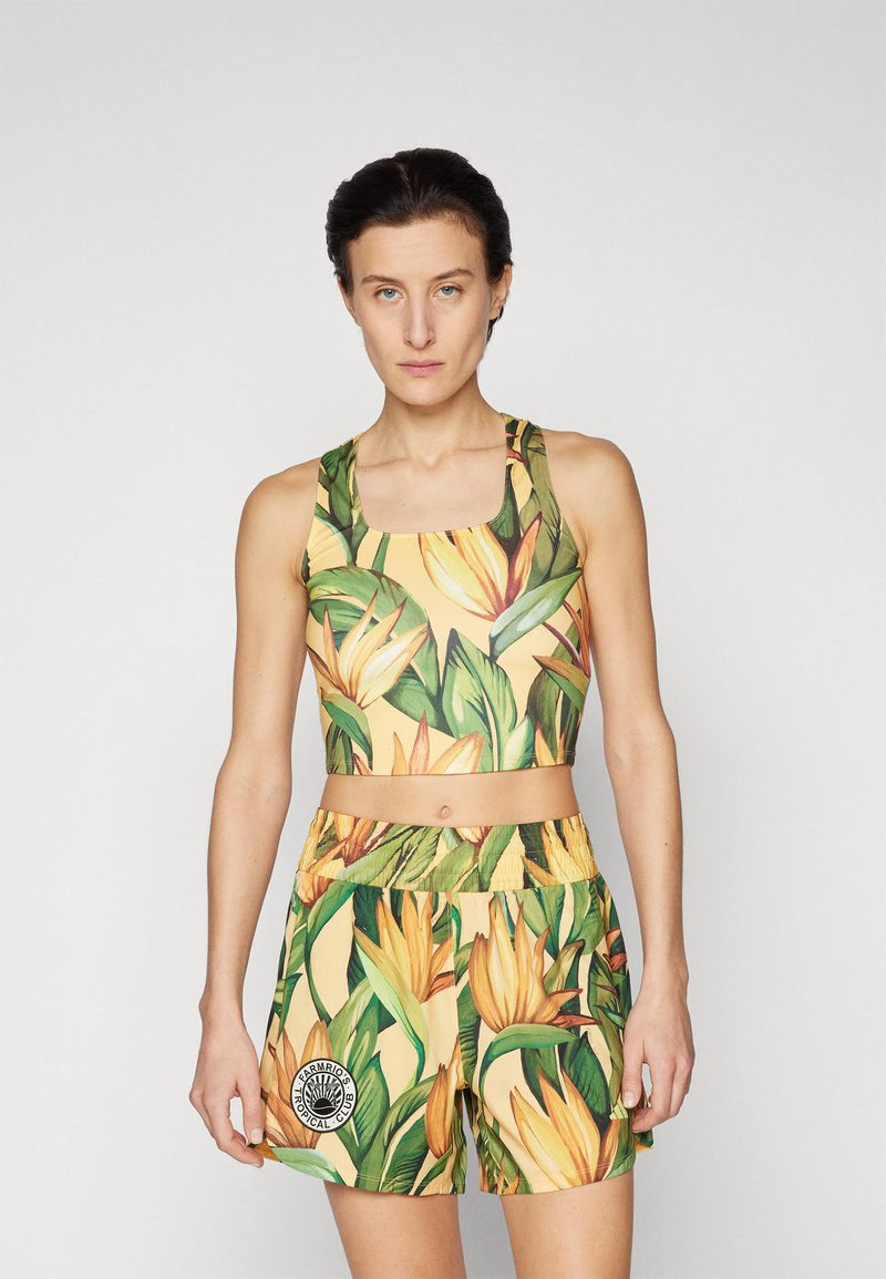 Completo sportivo con stampa tropicale in giallo e verde, composto da un top con scollatura quadrata e pantaloni corti con vita elasticizzata e dettaglio con emblema.