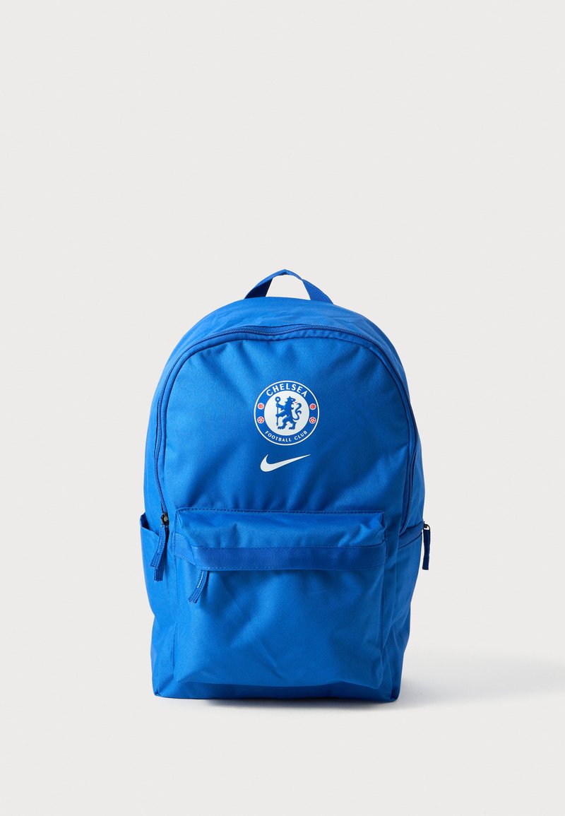 Mėlynas nailono kuprinė su priekinėmis užtrauktuku kišenėmis, Chelsea futbolo klubo logotipu ir Nike praėjimu. Suapvalinta forma su reguliuojamomis petnešomis.