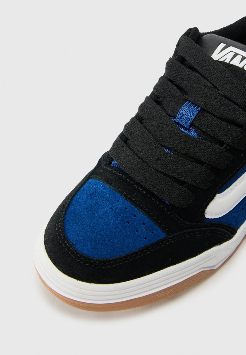 Zapatillas de ante negras y azules con detalles blancos, que presentan cordones anchos, una parte superior texturizada y una suela de goma de color goma.