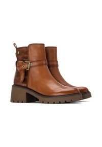Botas de tobillo de cuero marrón con un respaldo texturizado, una correa lateral con hebilla dorada y un tacón de goma grueso. Detalles de costura acentuada.