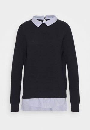 Pull noir texturé avec un col à rayures bleu clair en dessous, comportant une fermeture éclair au dos et des poignets et ourlet côtelés.