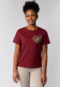 T-shirt en coton bordeaux à manches courtes et col rond, avec un design de cœur coloré comportant des illustrations de mains et d'objets.