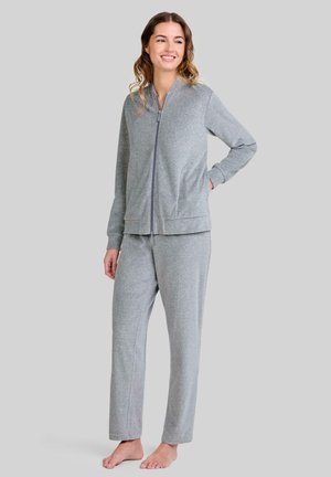 Chaqueta gris con cremallera y pantalones a juego de tejido suave, con mangas largas, cuello alto y diseño de pierna recta, llevados descalzo.
