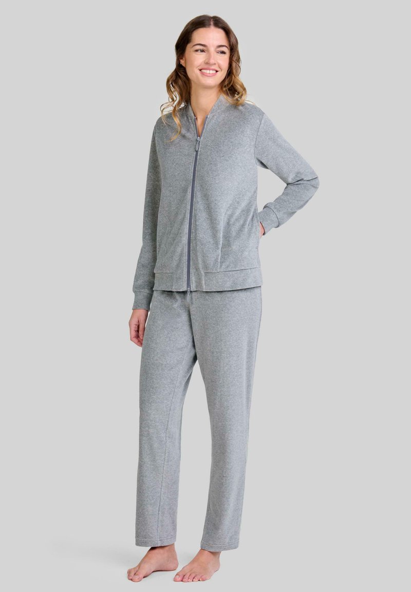 Chaqueta gris con cremallera y pantalones a juego de tejido suave, con mangas largas, cuello alto y diseño de pierna recta, llevados descalzo.