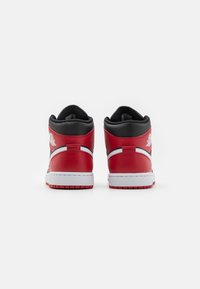 Sneaker alte con una tomaia in pelle rossa, dettagli neri, suola bianca e logo. Texture liscia con collare e linguetta imbottiti.