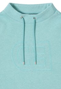 Sudadera azul claro con cuello alto, con capucha decorativa y cordones. En la parte delantera tiene un gran logo "CE" bordado.