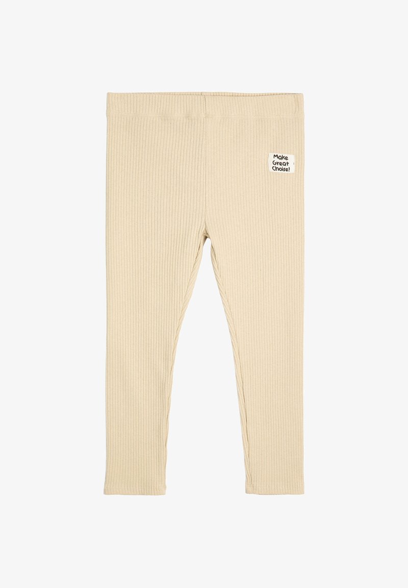 Beige Ripp-Leggings aus strukturiertem Stoff mit einem kleinen weißen Aufnäher am Taillenbund, auf dem steht "Treffe eine großartige Wahl!"