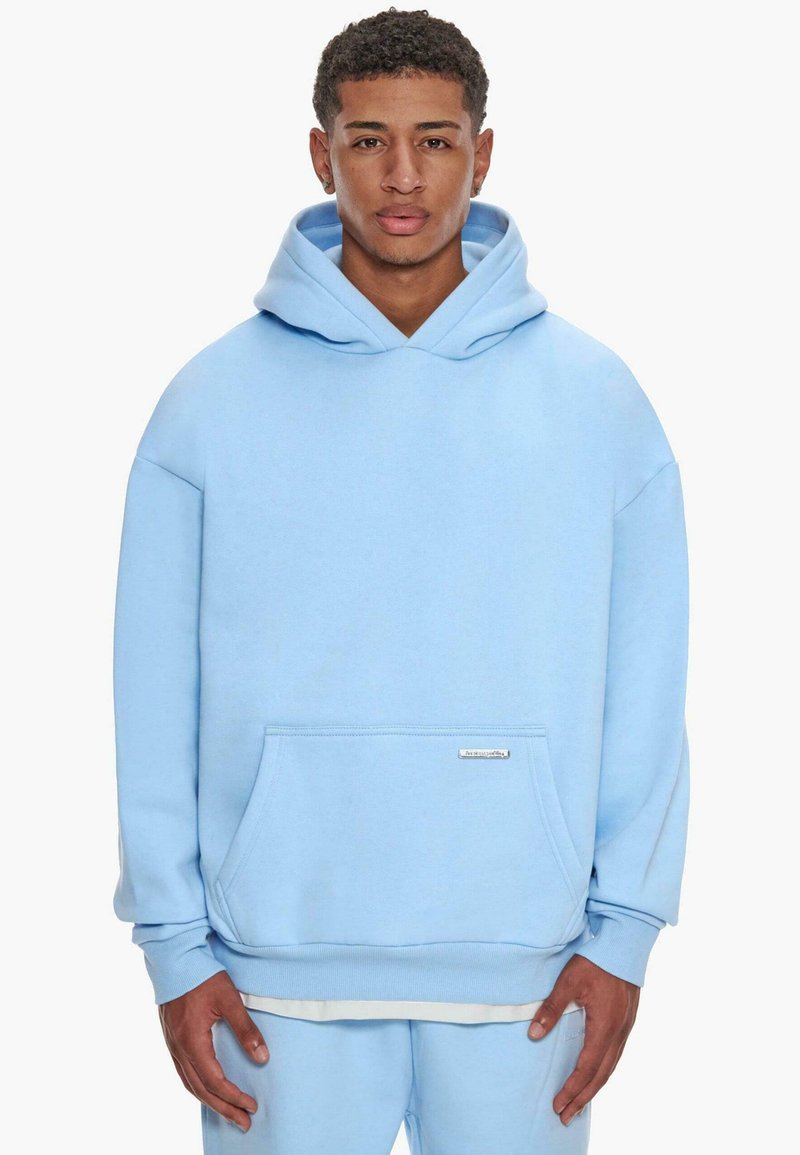 Light blue hooded sweatshirt made of soft fabric, featuring a front pocket and ribbed cuffs. Simple design without patterns or accents.