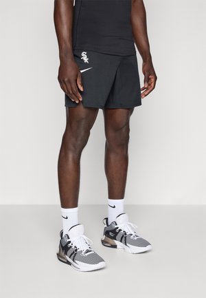 Homme portant un short de sport noir avec les logos blancs des Chicago White Sox et Nike, des chaussettes blanches Nike et des chaussures de course athlétiques noir et blanc.