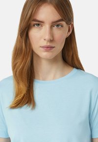 Lichtblauw T-shirt met korte mouwen en een ronde hals. Voorzien van subtiele branding op de voorkant. Zacht materiaal met een gladde textuur.