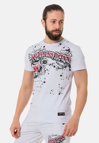 Witte katoenen t-shirt met een opvallende grafische print in rood en zwart, met een spetterontwerp en een merklabel aan de onderkant.