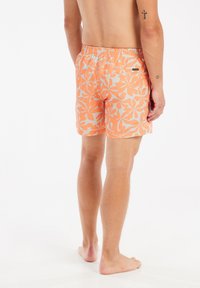 Oranje zwemboxers met een wit bloemenpatroon, elastische tailleband en een klein logo-etiket op de achterkant. Gemaakt van lichtgewicht, sneldrogend materiaal.