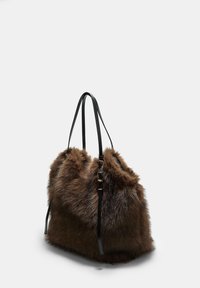 Brązowa torba tote z sztucznego futra o teksturowanym wykończeniu, z dwoma czarnymi skórzanymi uchwytami i zebranym wzorem u góry. Bez widocznych elementów metalowych.