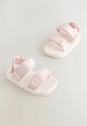 Rosa Sandalen mit glitzernden Riemen, ausgestattet mit zwei verstellbaren Klettverschlüssen und einer weichen Sohle. Verziert mit einem floralem Design auf dem Riemen.