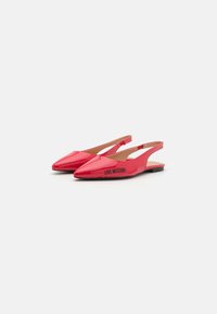 Sapatilhas slingback em pele envernizada rosa com bico apontado e pequeno salto preto. Apresenta o logótipo 'LOVE MOSCHINO' na lateral. Textura suave.