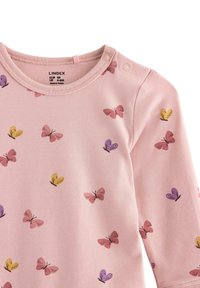 Lyserød babysovs med lange ærmer, dekoreret med gule, lilla og lyserøde sommerfuglemotiver, med trykknapper ved skuldrene.