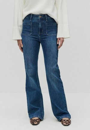 Utblåsta blå denimjeans med hög midja, två framfickor och kontrasterande sömmar. Därtill matchat med skor i djurtryck.