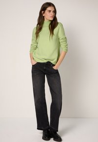 Vaaleanvihreä neulottu pooloneule, rento istuvuus; yhdistetty tummanharmaisiin leveälahkeisiin farkkuihin ja mustiin nilkkureihin. Yksinkertaista, tekstuuriltaan hienostunutta eleganssia.