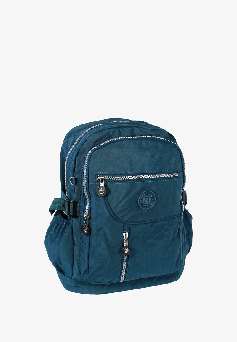 Sac à dos en tissu bleu marine avec plusieurs poches zippées, surface texturée, sangle verte réglable et un patch logo à l'avant.