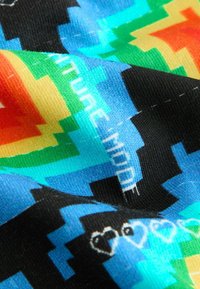 Bunte Stoffe mit einem pixelierten Muster und Herzmotiven in Rot-, Orange-, Blau-, Grün- und Schwarztönen. Weiches, strukturiertes Material.