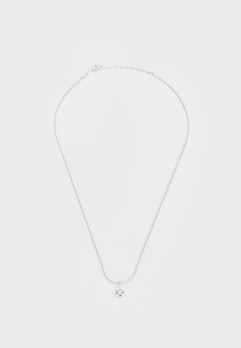 Hõbekaelakee peene ahela ja väikese ümmarguse ripatsiga, millel on selge kivi, näidates siledat tekstuuri ja lihtsat kujundust.