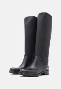 Črne gumijaste škornje za dež z visokim dizajnom do kolen, gladko teksturo, zaobljenim nosom in teksturiranim podplatom. Imajo diskretno logotip na strani.