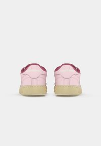Roze tenisice sa nubuk detaljima, gumeni potplat i Reebok oznaka na peti. Imaju zaobljeni vrh i dvobojni gornji dizajn.