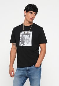 Black cotton t-shirt featuring a frontal graphic of a roaring polar bear within a square frame and abstract white patterns.