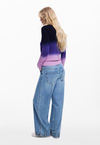 Pletený svetr s přechodem barev z tmavě modré do levandulové, doplněný volnými modrými džínami. Svetr má žebrované manžety a lem.