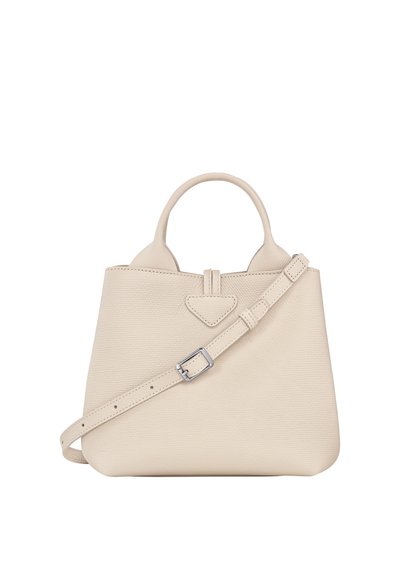 Beige leather handbag with a structured design, short top handles, adjustable strap, and a triangular accent on the front.