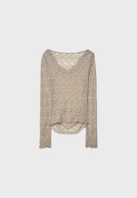 Langærmet top lavet af beige blonde med V-hals, struktureret diamantmønster og rundet kant. Bølgeformede kanter langs ærmerne og bunden.