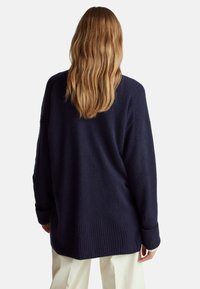 Navy oversized svetr s měkkou texturou, spadlými rameny a vroubkovanými manžetami. Nabízí volný střih a jednoduchý design.