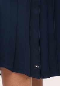 Σαλοπέτα ναυτικού στιλ με πτυχώσεις φτιαγμένη από υφασμένο ύφασμα, με μια μικρή λεπτομέρεια λογότυπου σε κόκκινο, λευκό και μπλε στην κάτω πλευρά.