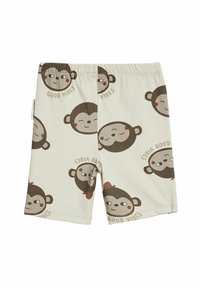 Shorts en coton avec un motif de visages de singe répété en marron sur un fond beige clair. Du texte "Good vibes" apparaît sous les visages.