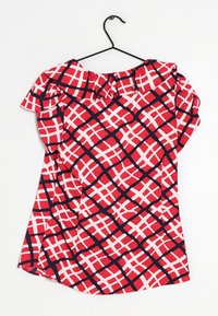 Maglietta rossa con motivo a griglia bianca e navy, dotata di scollatura arricciata e maniche corte, realizzata in tessuto leggero. Appesa a un gancio nero.
