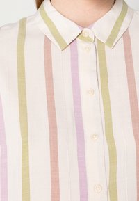 Camicia leggera in tessuto con righe verticali verde, rosa e lavanda. Presenta un colletto a punta e tre bottoni sul davanti.