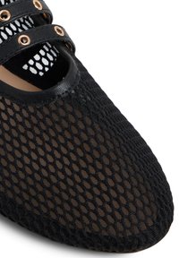 Scarpa Mary Jane nera in rete con doppie cinghie e occhielli dorati, che mostra dettagliati texture e cuciture su uno sfondo bianco.