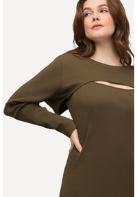 Zielonooliwkowy, prążkowany top z długim rękawem, z wycięciem na okrągłym dekolcie. Miękka faktura i luźny krój.