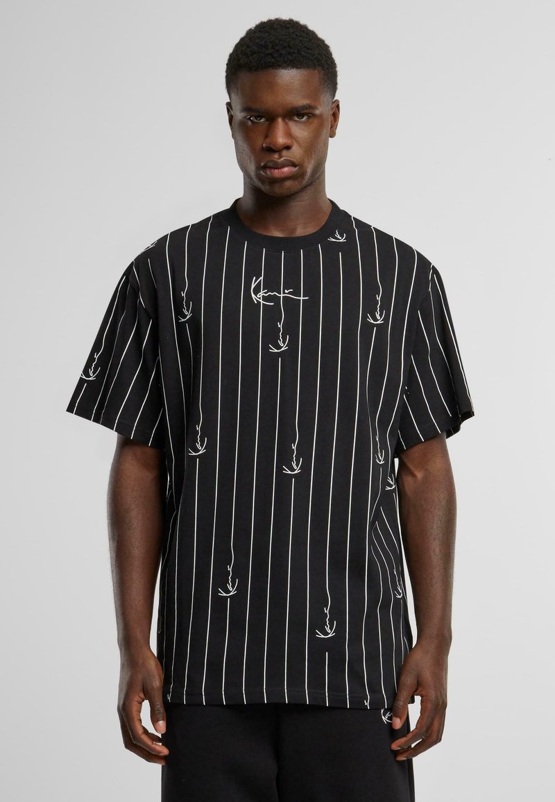 Black short-sleeve T-shirt featuring vertical white stripes and abstract white designs. Cotton material with a relaxed fit.
