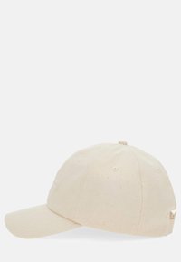 Casquette en coton beige avec une visière courbée, une sangle ajustable et une texture subtile. Présente des coutures tonales et des trous de ventilation.