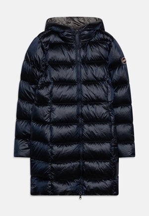 Long manteau d'hiver bleu marine matelassé avec capuche, fermeture à glissière frontale, piqûres horizontales matelassées et écusson logo sur la manche gauche.