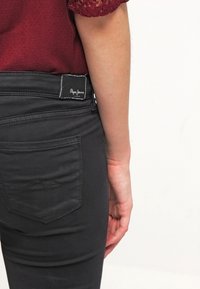 Svarta jeans med en åtsittande design, med en bakficka med sömdetalj och en varumärkeslapp placerad vid midjan.