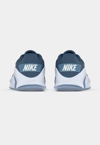 Chaussures de sport en tissu bleu avec une semelle blanche, présentant un logo Nike bien visible sur une bande accentuée bleu clair à l'arrière.